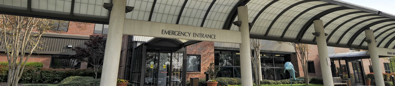 The exterior of an emergency entrance at a medical facility, with a covered walkway and glass doors.