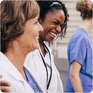 Two female doctors are laughing together in a hallway