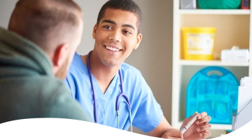 A doctor with a stethoscope around his neck smiles at a patient