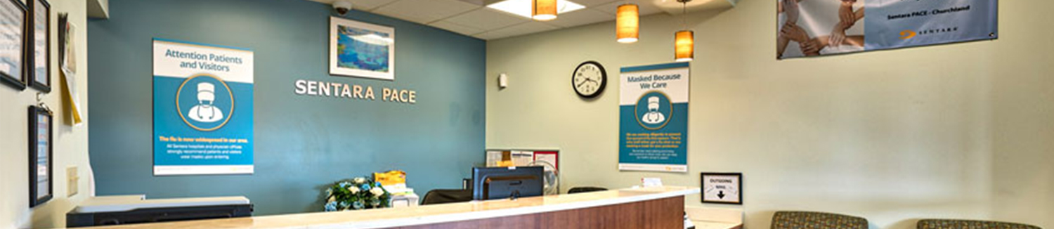 A front desk at Sentara PACE with signage about mask requirements and a welcoming, well-lit interior.
